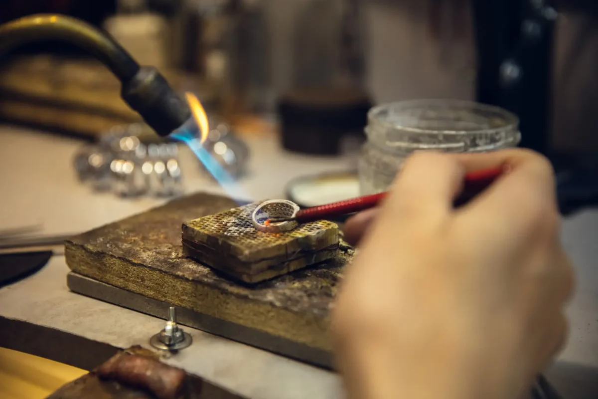 Close up hands of jeweller, goldsmiths making of golden ring with gemstone using professional tools. Craft production, precious and luxury jewel, hand made occupation. Workshop, artwork. SSUCv3H4sIAAAAAAAACnRSu27DMAzcC/QfDM01qvgZd+zQuXvRgZaYRIgiBZKcogjy76UsO9XQbuIdeSRPvD4+FAUbwSvBXoprjChWWk8+OAjKGoL504I7NBJdjlxc3fEcQKmCdQp0Do4QxMHACQk0k9YRvs0k8wHC5NHH7gskIOCeNBJ4l0gjfqS4WImZpAqi2Dvas0b2lDF+GiPDVii1+Kf+dfLKoPfPb8qAEX8qLT3ueunxuW4KezTi+3fuKO6QjLzgCdwRQ74CkZuqvmt9pscsuVjhUCMkd5YqBrtmFBsJpdwNsmwaLkpo266sW8G3vKm2O+SzZJqJHb8CulPuL0xS2czaixWgY0KddT47JZTZZ2U2HOa/X8uEnUxwcVe2GsW0tWcYyZ+XYkeauOIH8J7S5YpnjQRdmj1lfYwN88KLKpN0DjHc1FXbDQPnXddv+563/ZKQTuigSGceZxWiWByVzFdXcQKGmwr6euBl2/VV2YwdLweooOS8B/JWSJQ9WXj7AQAA//8DAI5EI7wdAwAA